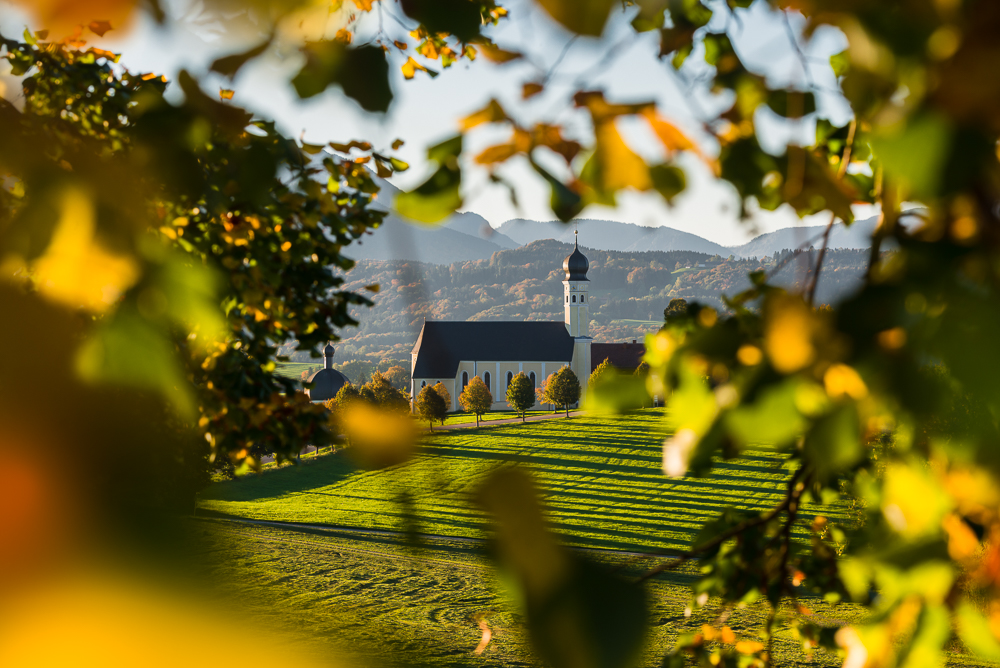 Die barocke Wallfahrtskirche in Wilparting eingerahmt von buntem Herbstlaub, Bayern, Deutschland