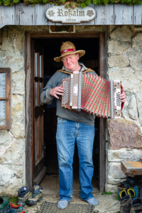 Almbauer musiziert auf seinem Akkordeon in der Hütte der Roßalm, Bayern, Deutschland