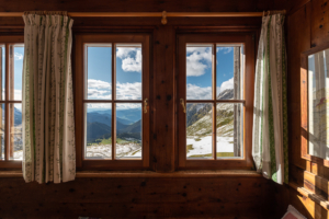 Ausblick durch ein Fenster in der Gaststube der Schlüterhütte auf das Villnößtal und die Sarntaler Alpen, Dolomiten, Südtirol, Italien