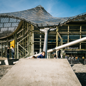 Kinder spielen auf den Betonbefestigungen der Stahlseile des Zeltdachs der Olympiahalle im Olympiapark, München, Deutschland
