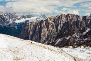 Zwei Wanderer beim Aufstieg zum Zendleser Kofel vor einer verschneiten Landschaft mit den Felswänden der Puez-Spitzen und dem Fanes-Sennes-Prags Bergmassiv in den Dolomiten im Herbst, Südtirol, Italien