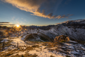 Die Morgensonne kommt über den Gipfeln der Fanes-Sennes-Prags-Gruppe der Dolomiten hervor und scheint auf das schneebedeckte Kreuzkofeljoch, Puez-Geisler-Gruppe, Südtirol, Italien
