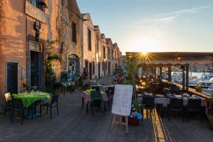 Abendessen bei Sonnenuntergang in einem Restaurant mit Livemusik in einem historischen Gebäude der ehemaligen Gerberei am Ufer des Flusses Temo in Bosa, Planargia, Sardinien