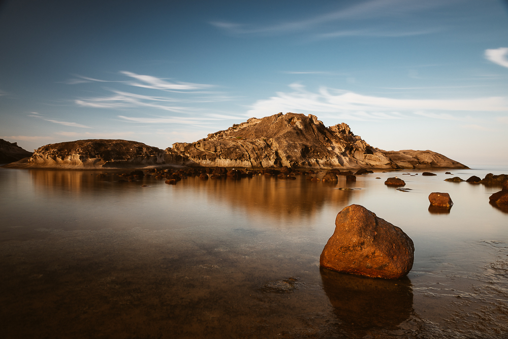 Felseninsel S'Isula de sas Crabas im Wasser einer Bucht am Torre Argentario an der Westküste von Sardinien in der warmen Morgensonne, Italien, Europa