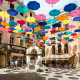 Bunte Sonnenschirme schützen die Passanten auf der von historischen Häusern umgebenen Piazza Lamarmora der Altstadt von Iglesias im Südwesten von Sardinien vor der heißen Mittagssonne, Iglesiente, Italien