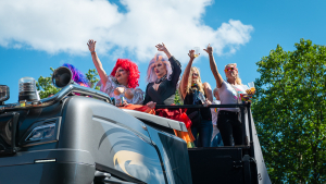 Bunt und fantasievoll gekleidete Teilnehmer der Christopher Street Day CSD Parade winken von einem Umzugswagen