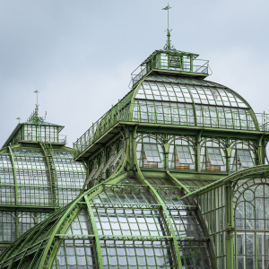 Die Kuppeln des Palmenhauses aus Schmeideeisen, Gusseisen und Glas im Schönbrunner Schloßpark unter einem bedeckten, grauen Himmel, Wien,. Österreich