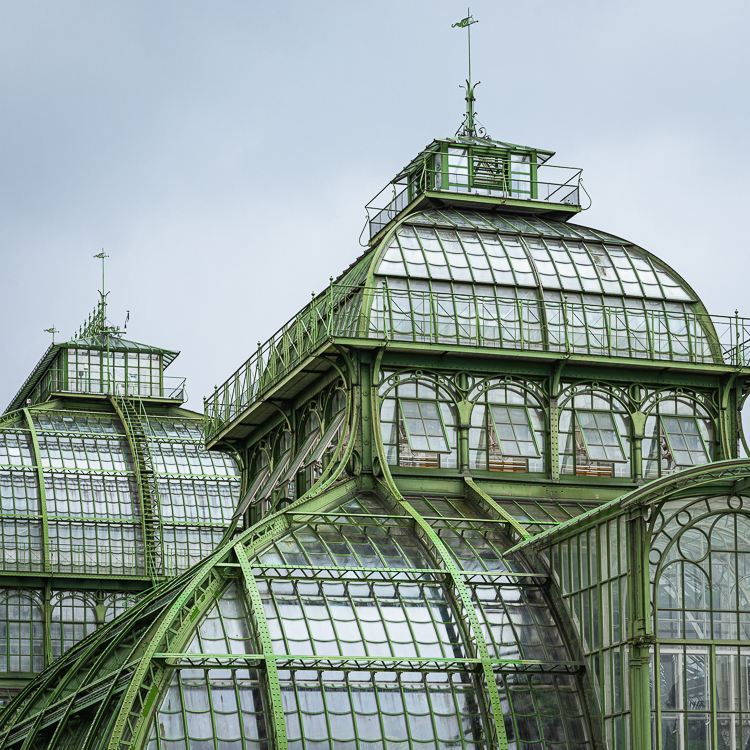 Die Kuppeln des Palmenhauses aus Schmiedeeisen, Gusseisen und Glas im Schönbrunner Schloßpark unter einem bedeckten, grauen Himmel, Wien,. Österreich