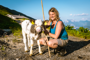 Sennerin Julia mit einen jungen Kalb beim Spaziergang auf der Ackernalm, Tirol, Österreich