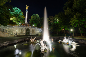 Springbrunnen mit Wasserfontänen, Figuren, Treppe und der Säule mit dem Friedensengel in nächtlicher Beleuchtung, Bogenhausen, München