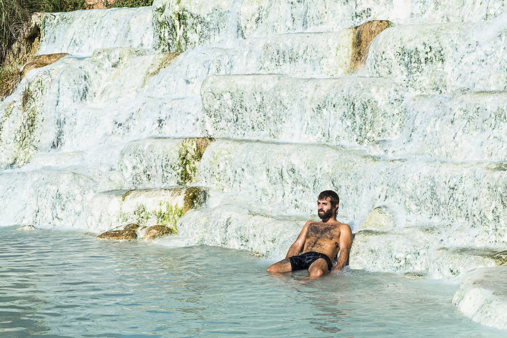 Ein Italiener sitzt in den Wasserkaskaden der heissen Thermalquellen von Saturnia, Toskana, Italien