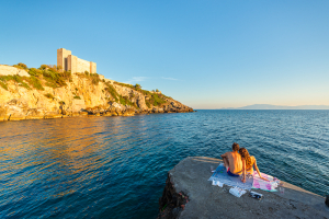 Die Burg Rocca Aldobrandesca an der Felsenküste der Maremma in Talamone im goldenen Sonnenuntergang, Toskana, Italien