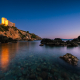 Die Burg Rocca Aldobrandesca an der Felsenküste der Maremma in Talamone im Zweilicht der Abenddämmerung, Toskana, Italien