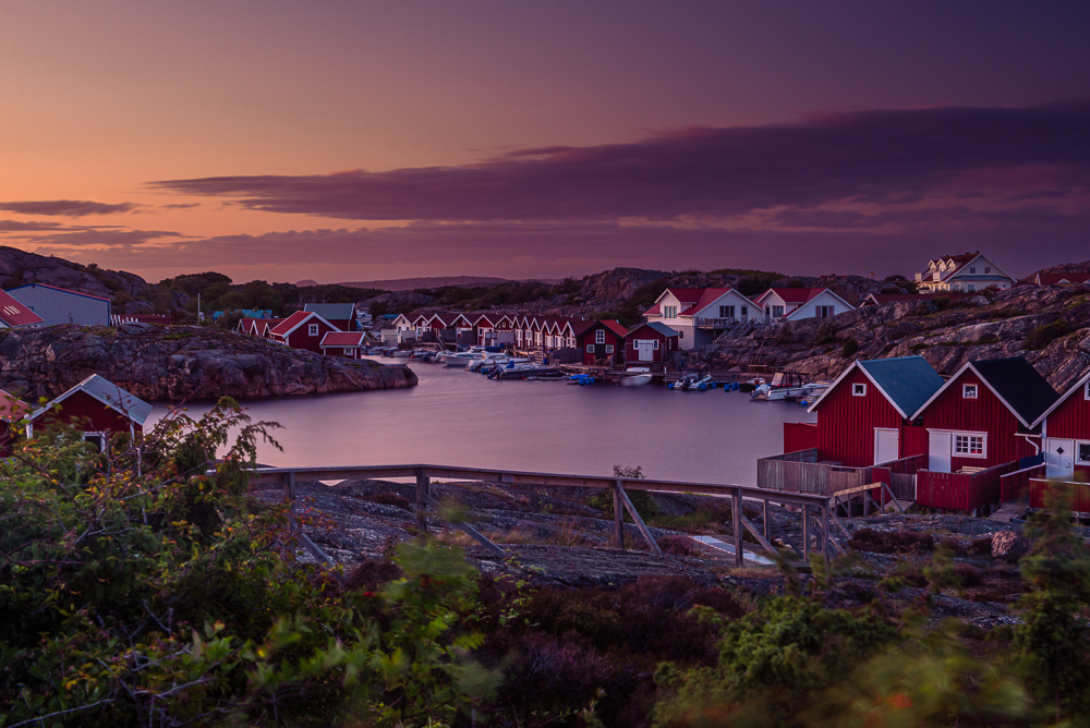Sonnenuntergang über Holzhütten und Bootshäusern an einer Bucht von Smögen in den Schären an der schwedischen Westküste