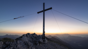 Das Gipfelkreuz auf dem Hinteren Sonnwendjoch im Gegenlicht der Morgendämmerung, Tirol, Österreich