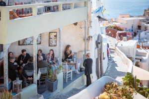 Männer und Frauen der Gemeinde der Heiligen Kirche der Taxiarchen sitzen nach dem Gottesdienst in einem Café von Oia, Santorin, Griechenland