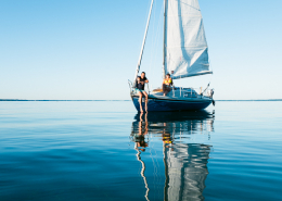Zwei Segler sitzen auf dem Segelboot auf dem Chiemsee, Bayern, Deutschland